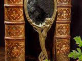 a mirror sitting on top of a table next to a bunch of books