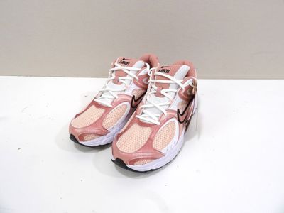chaussures de course Nike Air Presto roses et blanches posées sur une surface blanche