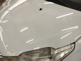 a close up of a white car with a hole in it ' s hood