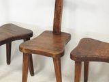 three wooden chairs and a stool are sitting on a white surface