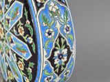 a blue and black vase with a floral design on it