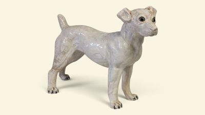 une petite statue représentant un chien debout sur une surface blanche