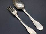 two silver spoons and a fork on a black surface