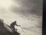 poster of a man skiing down a mountain with a sky in the background