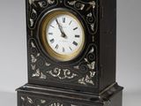 une horloge noire ornée d'un motif doré et blanc