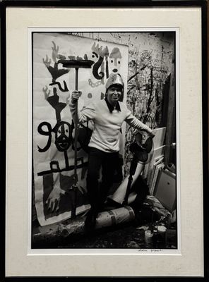 photographie en noir et blanc d'une femme debout devant un mur recouvert de graffitis