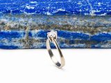 une image représentant une bague en diamant posée sur un morceau de marbre bleu