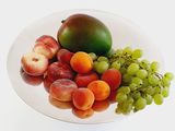 a plate of fruit on a white table with a white background