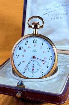 a gold pocket watch sitting in a case on a table