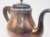 a silver tea pot sitting on a white surface