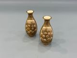 pair of small gold vases with flowers on them on a table