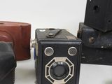 three old cameras are sitting next to each other on a white surface