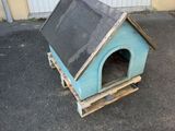 une petite niche pour chien fabriquée à partir de palettes, posée à même le sol