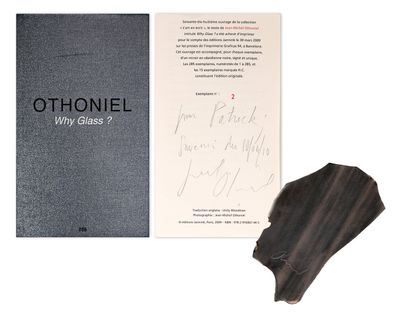 an open book sitting next to a piece of paper and a piece of wood
