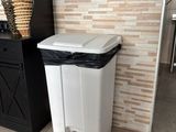 a white trash can sitting next to a black trash can