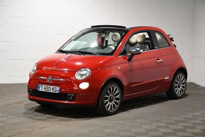 La petite voiture rouge est garée dans le garage, sur le sol à damier.