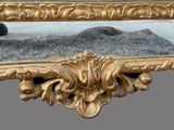 a mirror with a gold frame and a black hat