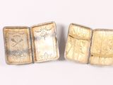 two gold bars are sitting next to each other on a white surface