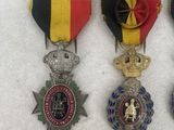 three medals are displayed on a white surface with a red, yellow, and blue ribbon