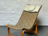 une chaise sur laquelle est posé un coussin, devant un mur de briques blanches