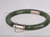 green bracelet with silver clasp and chain on display on clear surface