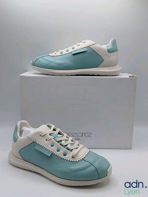 Les chaussures sont bleues et blanches, avec une semelle blanche.