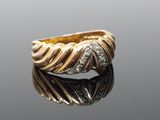 a close up of a gold and diamond ring on a reflective surface