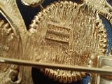 a close up of a gold brooch with a clock on it