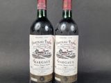 two bottles of red wine sitting next to each other on a table