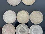 Six pièces de monnaie britanniques différentes sont exposées dans une vitrine.