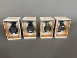 trois montres dans leurs boîtes, posées sur une table avec un fond gris