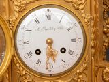 a gold clock with roman numerals on the face