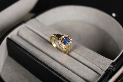 une bague en or sertie d'une pierre bleue, dans un écrin