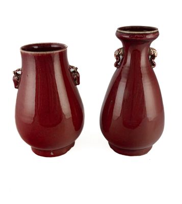 une paire de vases rouges munis d'anses de chaque côté d'un fond blanc