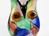 un vase en verre coloré orné d'un visage de chouette