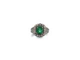 gros plan d'une bague avec une pierre verte entourée de diamants