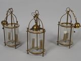 three brass and glass lanterns on a white background
