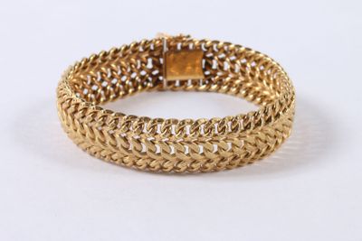 gros plan d'un bracelet en or sur une surface blanche