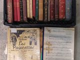 un panier rempli de livres posé par terre à côté d'une bibliothèque