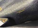 un gros plan d'un sac à main noir orné d'un logo doré