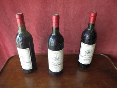 three bottles of wine sit on a wooden table in front of a red background