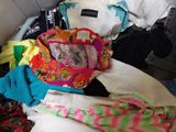 un tas de vêtements et un sac à main posés sur un lit