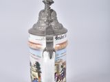 a beer mug with a statue on top of it