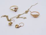 trois bagues en or, un collier et une bague posés sur un fond blanc