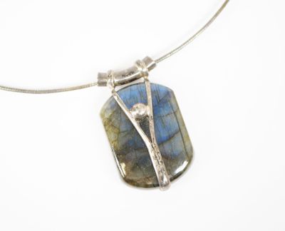 un gros plan d'un collier orné d'une pierre bleue montée sur une chaîne en argent