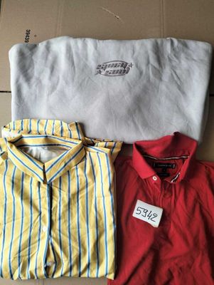 Trois chemises pour homme et un t-shirt sont posés sur une boîte en carton