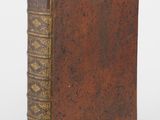 an old book with a brown cover sitting on top of a white surface