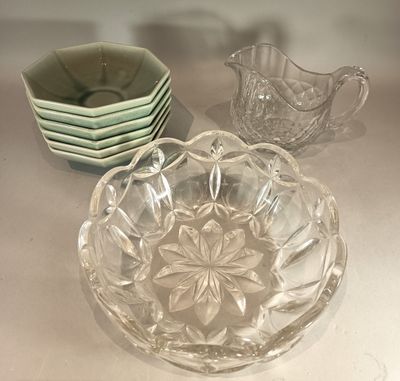a glass bowl sitting on a table next to a bowl of dishes