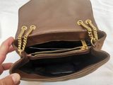 someone is holding a brown purse with a gold chain around it