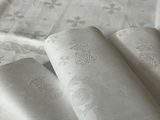 trois serviettes pliées posées sur une table recouverte d'une nappe blanche